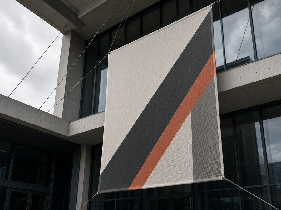 Scrim vinyl banner hung by cables from a concrete and glass building facade